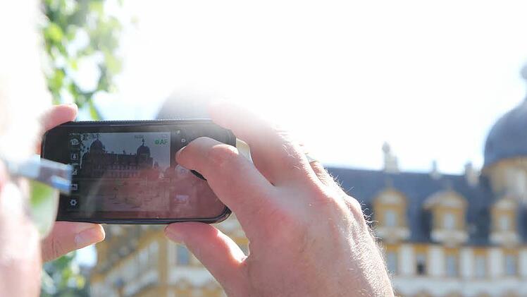 Ein Tourist fotografiert das Schloss Seehof in Memmelsdorf. Foto: Michael Gründel/Archiv