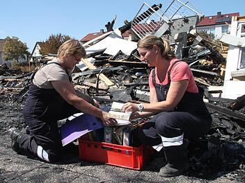 Monika Hofffmann (rechts) und Daniela Seifert-Schneider haben in einer Wanne Ordner gesammelt, die nicht verbrannt sind. Monika Hoffmann hält ein Gesangbuch in der Hand, das relativ unversehrt ist. Foto: Alexander Hartmann