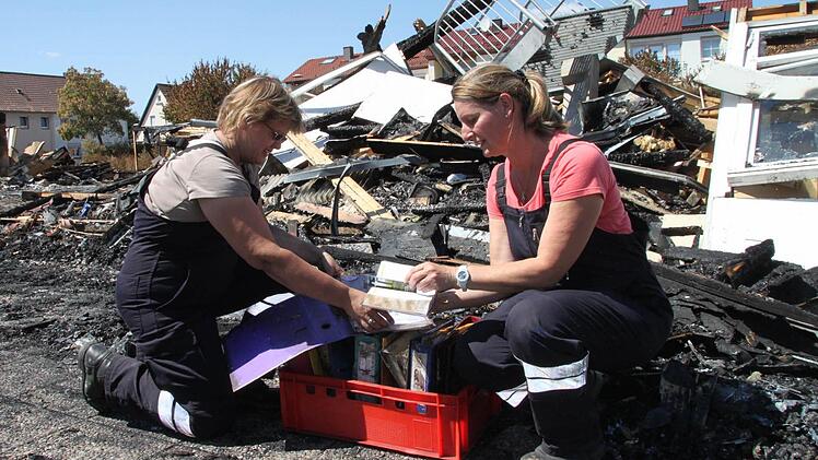 Monika Hofffmann (rechts) und Daniela Seifert-Schneider haben in einer Wanne Ordner gesammelt, die nicht verbrannt sind. Monika Hoffmann hält ein Gesangbuch in der Hand, das relativ unversehrt ist. Foto: Alexander Hartmann