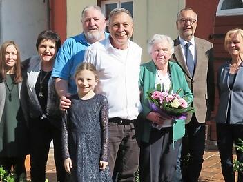 Fototermin im frühlingshaften Garten: Schwiegertochter Tanja, Tochter Martina, Sohn Günter, Enkelin Ella, Sohn Michael, Anna Thyzel (mit Blumenstrauß), Bürgermeister Jürgen Kohmann und Ortssprecherin Bärbel Köcheler Foto: Monika Schütz