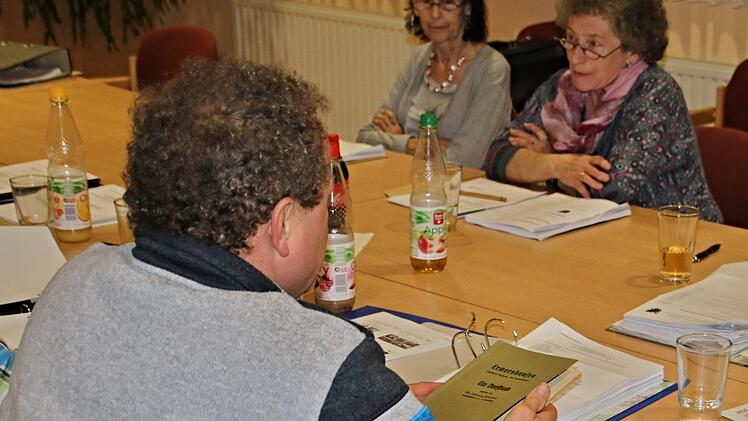 Zweitem Bürgermeister Klaus Welz über die Schulter geblickt: Er hält das Dorfbuch von Ermershausen in der Hand, das eventuell zum 975-jährigen Bestehen der Gemeinde neu aufgelegt werden soll. Ihm gegenüber sitzen die Gemeinderätinnen Lydia Steuter (FW) und Gertrud Pößnecker (FW).Helmut Will