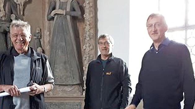Herbert M&uuml;ller, Wilhelm Keim, und Pfarrer Gerald Munzert (von links) pr&auml;sentieren den restaurierten Taufstein.  Foto: privat