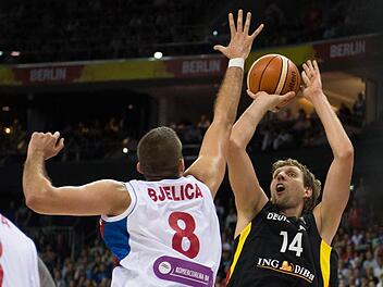 Dirk Nowitzki (rechts) versucht gegen den ausgestreckten Arm von Serbiens Matchwinner, Nemanja Bjelica, einen schwierigen Wurf. Foto: Lukas Schulze/dpa