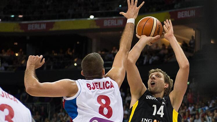 Dirk Nowitzki (rechts) versucht gegen den ausgestreckten Arm von Serbiens Matchwinner, Nemanja Bjelica, einen schwierigen Wurf. Foto: Lukas Schulze/dpa