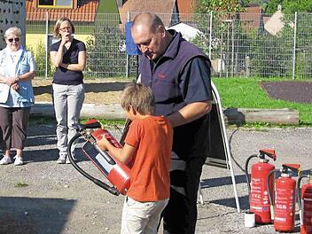 Thomas Walter zeigt einem Grundschüler den richtigen Umgang mit dem Handfeuerlöscher. Foto: Grams