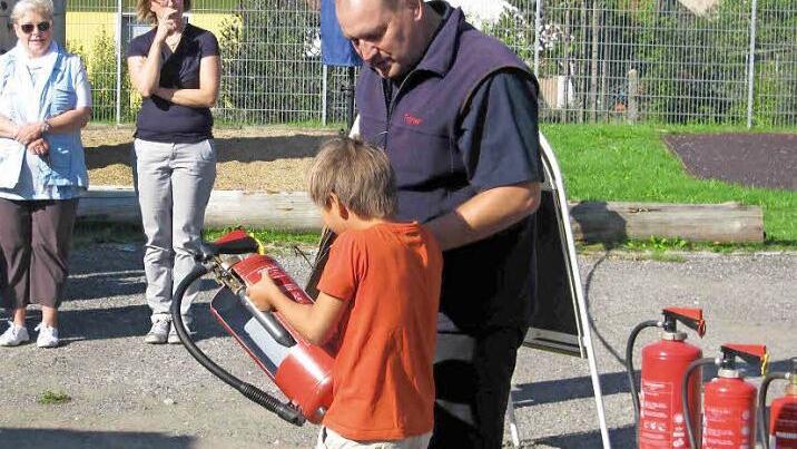 Thomas Walter zeigt einem Grundschüler den richtigen Umgang mit dem Handfeuerlöscher. Foto: Grams