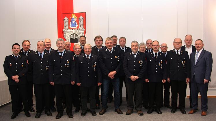 Landrat Thomas Bold (re.) und Bürgermeister Helmut Blank (2.v.e)sowie Kreisbrandmeister Andreas Klopf (links) und Kreisbrandrat Benno Meth (2.v.l) mit den Männern, die seit 40 Jahren der Münnerstädter Feuerwehr die Treue halten. Foto: Matthias  Nöth