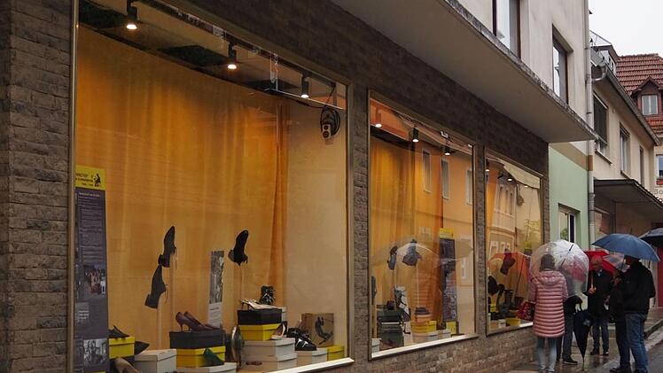 Einige Besucher kamen zur Eröffnung der Ausstellung und trotzten dem Regen. In den Schaufenstern sind Schuhe aus verschiedenen Jahrzehnten zu sehen. Die Informationstafeln in den "Vitrinen" ordnen die Exponate in den geschichtlichen Zusammenhang ein.  Foto: Rebecca Haas