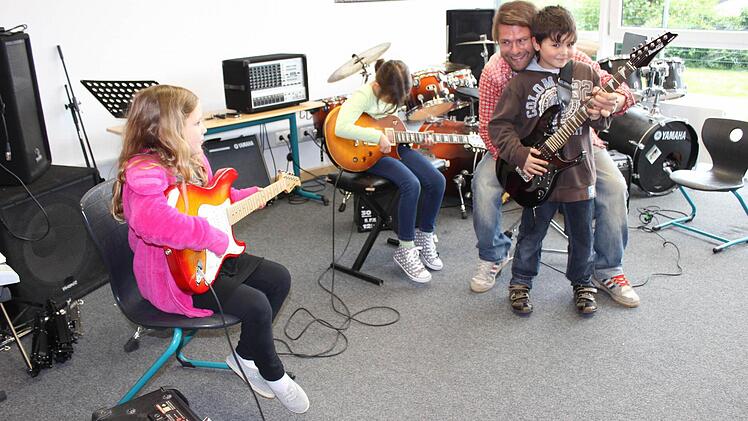 Sascha Weibart zeigt Kindern, wie man Gitarre spielt. Foto: fra-press
