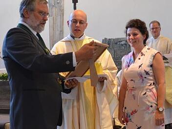 Franz Wachter von der Kirchenverwaltung und Pfarrgemeinderatsvorsitzende Katja Quidenus überreichen Christian Müllner eine Torte mit seinem Bild von der Priesterweihe sowie eine Urkunde, auf der alle Geschenke gelistet waren; rechts hinten Dekan Lars Rebhan. Fotos: Thomas Micheel