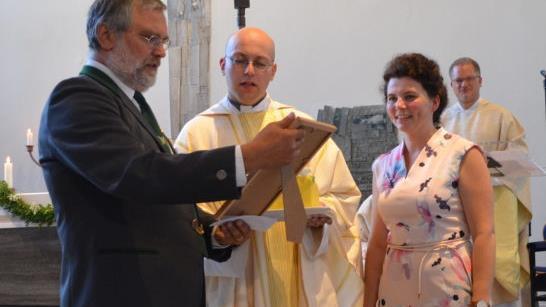 Franz Wachter von der Kirchenverwaltung und Pfarrgemeinderatsvorsitzende Katja Quidenus überreichen Christian Müllner eine Torte mit seinem Bild von der Priesterweihe sowie eine Urkunde, auf der alle Geschenke gelistet waren; rechts hinten Dekan Lars Rebhan. Fotos: Thomas Micheel