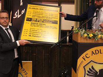 Schirmherr B&uuml;rgermeister Markus M&ouml;nch (rechts) &uuml;bergab das Plakat der Sportplatzeinweihung aus dem Jahr 1979 an Vorsitzenden Thomas Eckstein. Vom ehemaligen K&auml;mmerer der Gemeinde Gerhard Friedrich wurde es sorgsam aufbewahrt. - Foto: Alexandra Kemnitzer