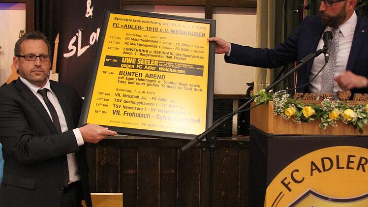 Schirmherr B&uuml;rgermeister Markus M&ouml;nch (rechts) &uuml;bergab das Plakat der Sportplatzeinweihung aus dem Jahr 1979 an Vorsitzenden Thomas Eckstein. Vom ehemaligen K&auml;mmerer der Gemeinde Gerhard Friedrich wurde es sorgsam aufbewahrt. - Foto: Alexandra Kemnitzer