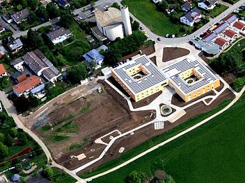 Auf der Fläche links neben den beiden quadratischen Gebäuden (Seniorenzentrum) entsteht das Service-Wohnen. Im unteren Bereich nimmt der Bürgerpark Gestalt an, rechts im Bild sieht man die Kindertagesstätte, links außen einen Teil der Schule.  Lufttbild: Adolf Nüßlein