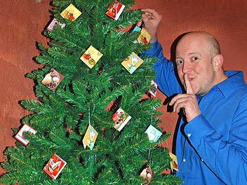 Arnd Rühlmannn vor dem Weihnachtsbaum mit all den Kärtchen, die zu Texten führen Foto: pr