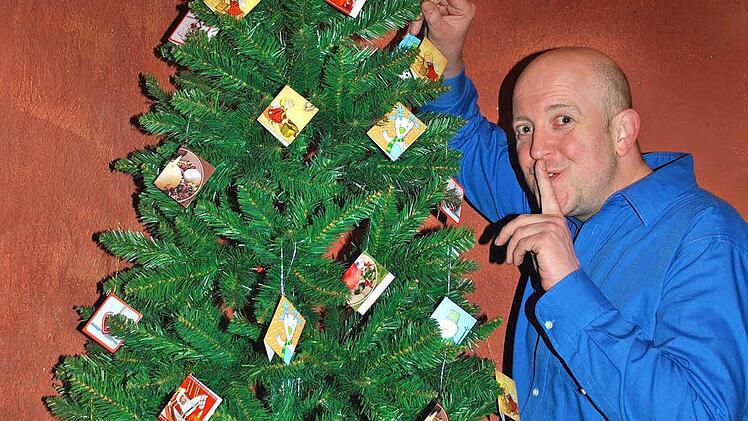Arnd Rühlmannn vor dem Weihnachtsbaum mit all den Kärtchen, die zu Texten führen Foto: pr