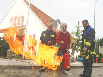 Pfarrerin Christine Seitzinger wird von den Feuerwehrprofis Thomas Schneider (rechts) und Bernd Nitsche in den Umgang mit dem Feuerlöscher eingewiesen. Fotos: Michael Busch