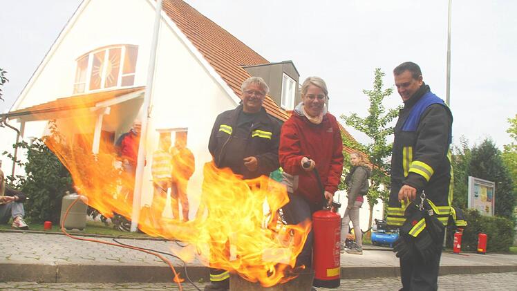 Pfarrerin Christine Seitzinger wird von den Feuerwehrprofis Thomas Schneider (rechts) und Bernd Nitsche in den Umgang mit dem Feuerlöscher eingewiesen. Fotos: Michael Busch