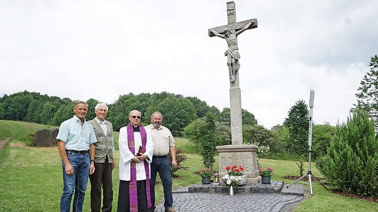 Familie Söder kümmert sich um das "weiße Kreuz" oberhalb von Sandberg. Die Restaurierung und Neugestaltung der Anlage wurde mit einem kleinen Fest zum 60-jährigen Jagdjubiläum von Gustav Söder verbunden (von links): stellvertretender Bürgermeister Claus Kleinhenz, Gustav Söder, Pfarrer Hubert Grütz und Wolfgang Söder.  Foto: Marion Eckert