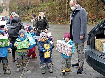 Stolz präsentieren die Kleinen der Trebgaster Kita ihre Päckchen, bevor sie von Round Table-Mitglied Florian Drechsler (rechts) eingeladen werden.