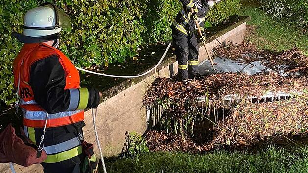 Die Feuerwehr war gefordert: Hier reinigen Wehrkräfte nach dem starken Gewitter das Einlaufschutzgitter einer Kanalverrohrung von angeschwemmtem Laub und Ästen.