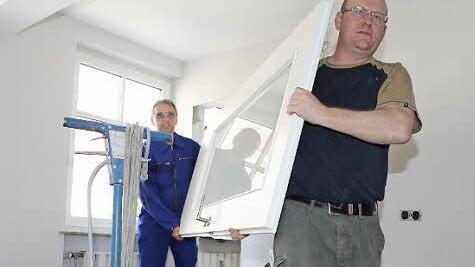Wegen des bruchsicheren Sicherheitsglases sind die Türen ganz schön schwer, die Friedwald Schedel und Thomas Schmidt (von links) zum Einhängen in den Türrahmen trugen. Dabei durften sie nicht über die vielen gelagerten Materialien stolpern. Foto: Matthias Hoch