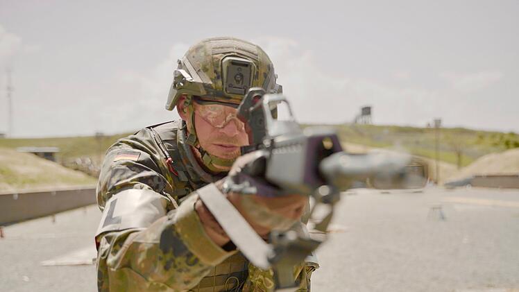 Peter zeigt jungen Soldaten am Schie&szlig;stand den Umgang mit der Waffe.