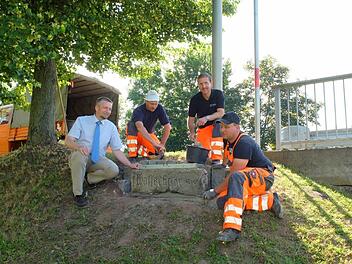 Bürgermeister Ralf Nowak (links) freut sich, dass Kraisdorf ein geschichtliches Dokument aus Sandstein zurückbekommen hat. Roland Hartenfels, Ingo Lurz und Bernd Hubert vom Bauhof Pfarrweisach haben den zentnerschweren Quader mit der Hochwassermarke an der neuen Brücke von Kraisdorf gesetzt.  Fotos: pp