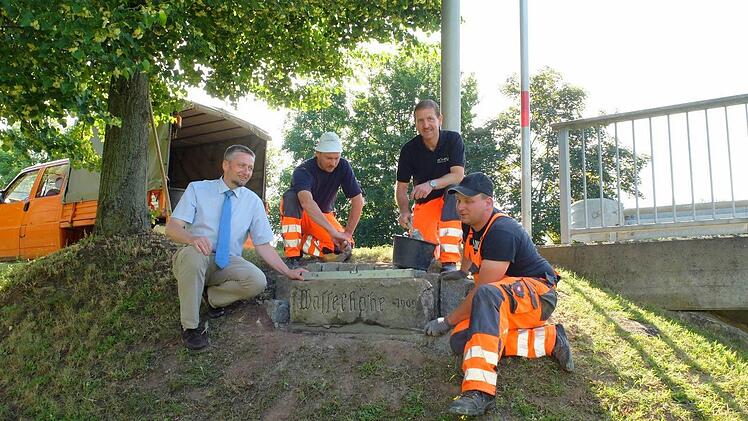 Bürgermeister Ralf Nowak (links) freut sich, dass Kraisdorf ein geschichtliches Dokument aus Sandstein zurückbekommen hat. Roland Hartenfels, Ingo Lurz und Bernd Hubert vom Bauhof Pfarrweisach haben den zentnerschweren Quader mit der Hochwassermarke an der neuen Brücke von Kraisdorf gesetzt.  Fotos: pp