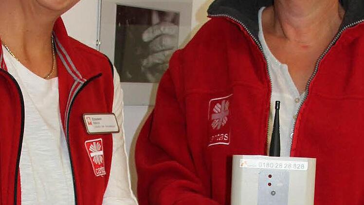 Auf Bewegungen reagiert die Notruf-Uhr, die Bettina Eckstein (links) zeigt; über die Basis-Station (präsentiert von Sabine Paeth, rechts) werden die Signale an die Rettungsleitstelle weitergegeben, über die auch Rückrufe möglich sind. Foto: Ralf Kestel
