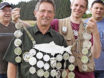 Der Vorjahres-Fischerkönig Bastian Trenner überreichte die Königskette an Bernhard Gluth aus Silberstein. Mit im Bild im Hintergrund Vorsitzender Dieter Raldo (links) sowie sein Stellvertreter Timo Michel (rechts).  Foto: Michael Wunder