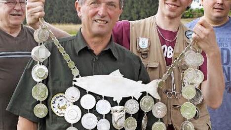 Der Vorjahres-Fischerkönig Bastian Trenner überreichte die Königskette an Bernhard Gluth aus Silberstein. Mit im Bild im Hintergrund Vorsitzender Dieter Raldo (links) sowie sein Stellvertreter Timo Michel (rechts).  Foto: Michael Wunder