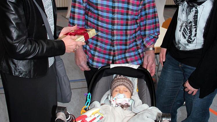 Zweite Bürgermeisterin Jutta Köhler, der stolze Opa Willi Schmidt und Mutter Stefanie Roß betrachten die neun Monate alte Natalie, die die Übergabe ihres Geschenks verschläft. Foto: Johanna Blum
