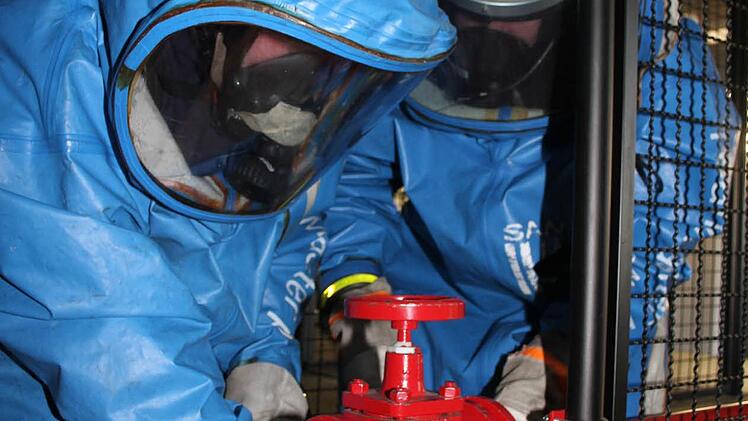 In der Atemschutzstrecke bauen die Feuerwehrler einen Schieber aus. Gar nicht so einfach mit den schweren Schutzhandschuhen und den flüssigkeits- und gasdichten Anzügen.  Fotos: Sonja Adam