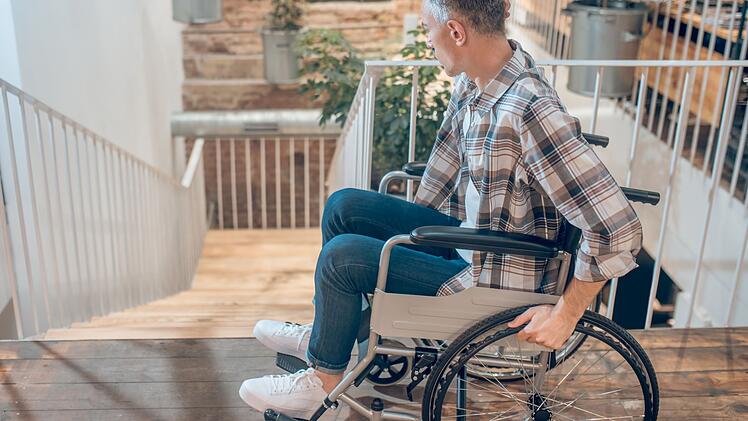 Man on wheelchair near steps down indoors