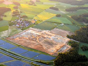 Der Ort Feulersdorf (Hintergrund, links) wirkt im Vergleich zur Großbaustelle geradezu mickrig. Zwölf Hektar groß ist die Fläche, auf der seit vielen Wochen die Erdarbeiten für die Gemüsefarm laufen. Zwischen den Photovoltaik-Anlagen ist die A 70 zu sehen. Fotos: Axel Emersleben