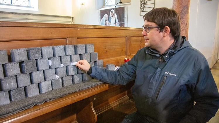 Persönliche Anliegen können, auf Zetteln niedergeschrieben, in die Ritzen einer "Klagemauer" gesteckt werden, so wie es Diakon Marco Schindler hier demonstriert. Fotos: Klaus Gagel