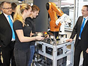 "Das ist unser Azubi-Projekt, das haben wir selbst gebaut", schwärzem die Auszubildenden Daniela Koch und Andreas Schlaf vom Arbeitsplatz mit dem Roboter, der Kunststoffteile für die Autoindustrie aus der Presse nehmen und lasern kann. Mit im Bild (von links): Geschäftsführer Vertrieb Hermann Fischer, Ausbildungsleiter Tobias Geiger und Geschäftsführer Technik Arthur Schwab.  Foto: Friedwald Schedel