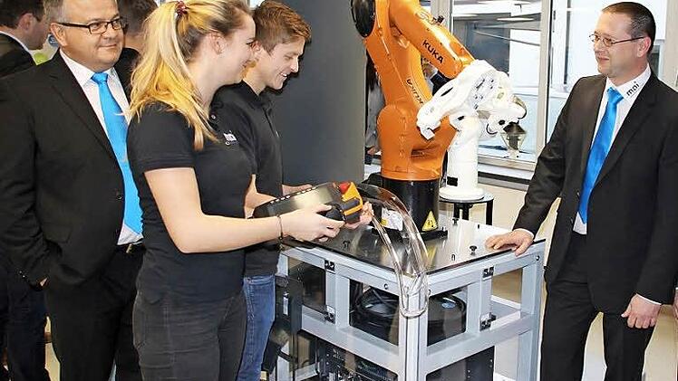 "Das ist unser Azubi-Projekt, das haben wir selbst gebaut", schwärzem die Auszubildenden Daniela Koch und Andreas Schlaf vom Arbeitsplatz mit dem Roboter, der Kunststoffteile für die Autoindustrie aus der Presse nehmen und lasern kann. Mit im Bild (von links): Geschäftsführer Vertrieb Hermann Fischer, Ausbildungsleiter Tobias Geiger und Geschäftsführer Technik Arthur Schwab.  Foto: Friedwald Schedel