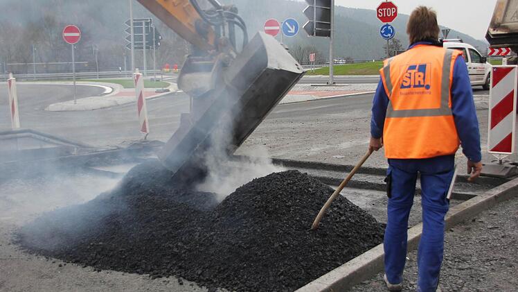 Mit der Baggerschaufel und per Hand wird der Asphalt breit gemacht. Foto: Friedwald Schedel
