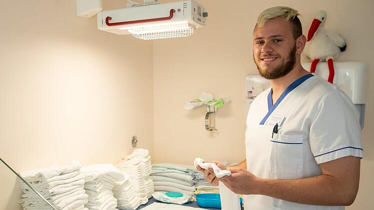 Bayern, Ansbach: Konstantin Wroblewski, Entbindungspfleger in der Ausbildung an der Berufsfachschule für Hebammen und Entbindungspfleger am Klinikum Ansbach, bereitet in einem Stillzimmer auf der Geburtshilfe-Station einen Wickeltisch für die Baby-Visite vor. Foto: Daniel Karmann/dpa