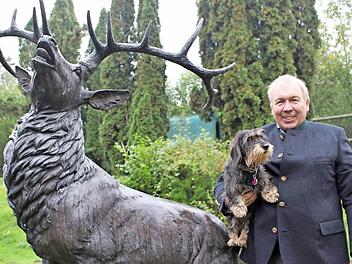 Harm Humburg mit seinem Jagdhund Anni vor einer alten, in Kupfer gegossenen Hirschplastik auf seinem Hof in Zeitlofs. Foto: Julia Raab