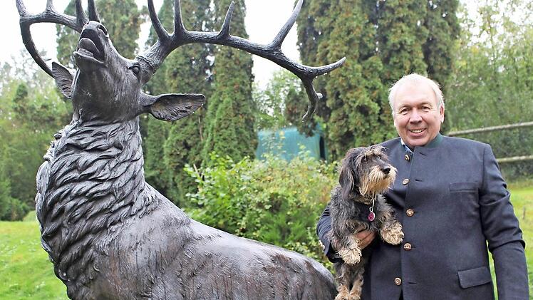 Harm Humburg mit seinem Jagdhund Anni vor einer alten, in Kupfer gegossenen Hirschplastik auf seinem Hof in Zeitlofs. Foto: Julia Raab