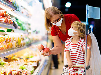 Mother and child buying fruit in supermarket.