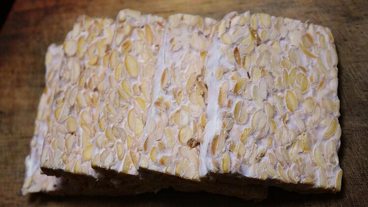Tempeh erinnert optisch eher an weißen Nougat, verrät sich aber spätestens im Geschmack. Durch die Zugabe von Edelschimmelpilzen entsteht nämlich ein pilzig-nussiges Aroma.