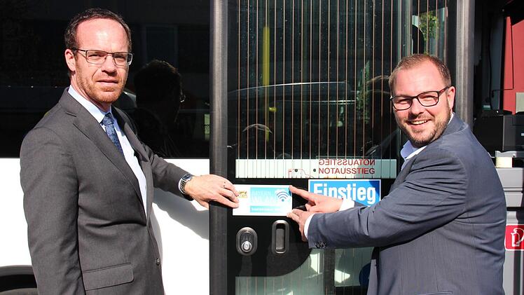 Geschäftsführer der Omnibusverkehr Franken und Landrat Sebastian Straubel bringen den wichtigen Hinweis an. Foto: Niklas Schmitt