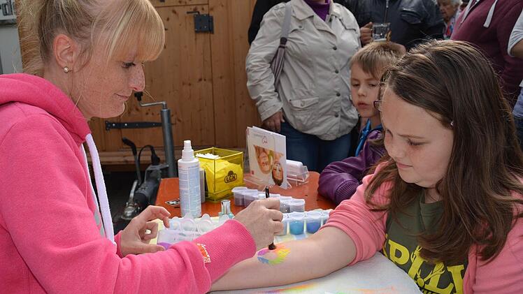 Die Windheimerin Stephanie Stahl war bei den Kindern wegen ihrer Glitzertatoos sehr gefragt. Hier verschönert sie den Arm von Selina mit einem Feuerherz. Foto: Kathrin Kupka-Hahn