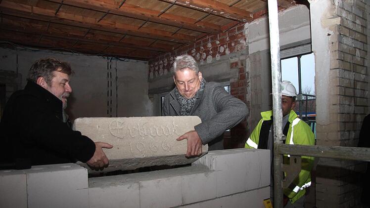 Bürgermeister Horst Rehder und Architekt Mario Bodem heben den Grundstein an seinen neuen Platz.