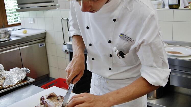 Anton Derkatsch (18), Koch-Azubi in der DRV-Klinik Saale, beim Aufschneiden des Kaninchen-Bratens. Foto: Sigismund von Dobschütz