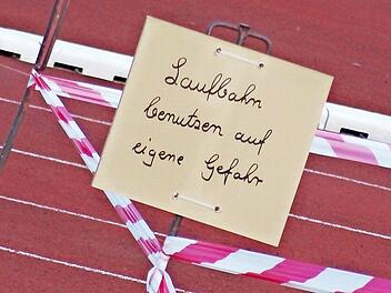 Vor der Tartanbahn weisen zwei handgeschriebene Schilder auf die Schäden hin. Foto: Jochen Berger